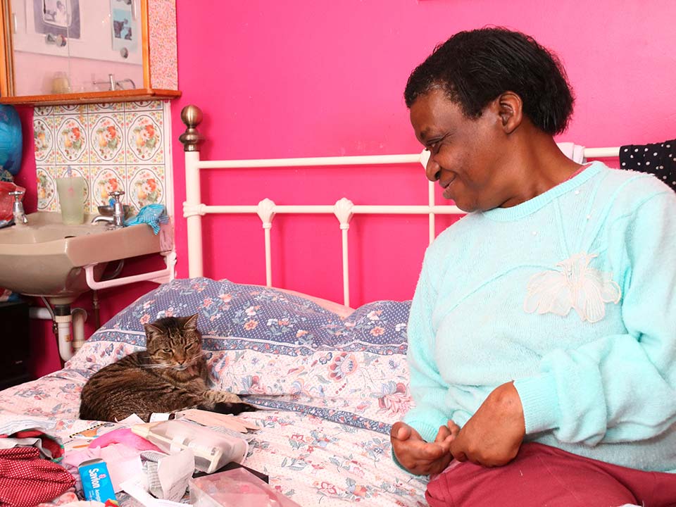 Woman looking at small cat on bed