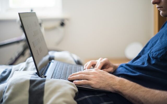 Typing on a laptop in bed