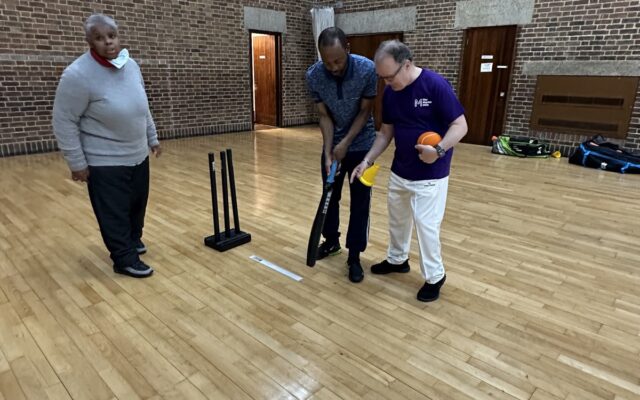 Person being coached in cricket in gym