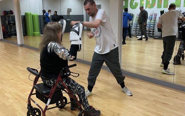 Man and woman in mobility aid boxing in gym