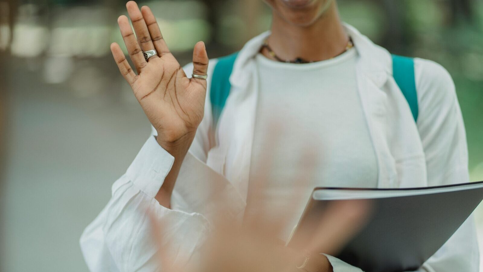 Woman waving hello with binder