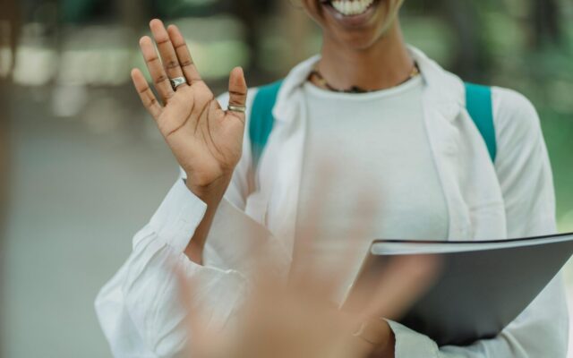 Woman waving hello with binder
